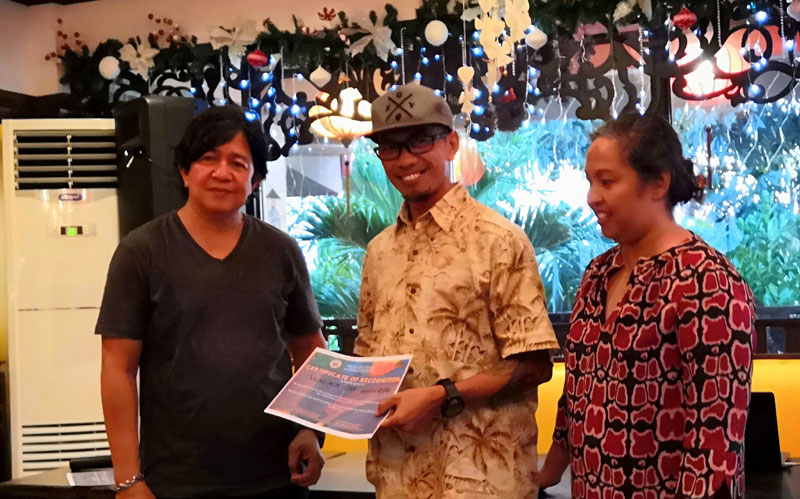 Committee members PG Zoluaga (left) and Leny Ledesma (right) award Vladimir Guanzon as winner of Iloilo Summer Arts Festival logo making contest.