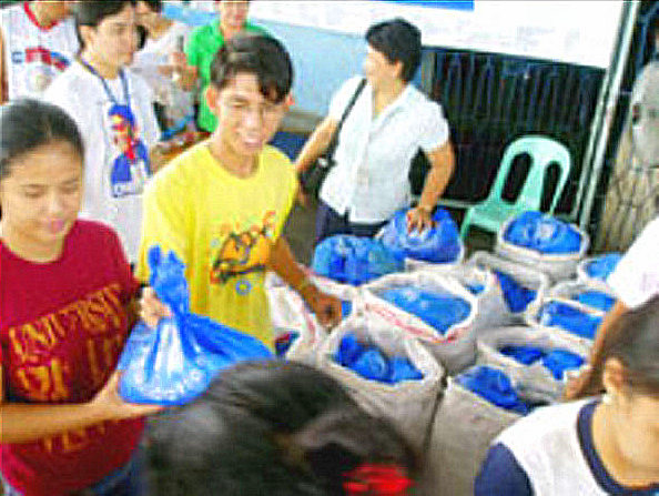 Shayne(leftmost) volunteers for SMFI Share Your Extras distribution at Brgy Boulevard Molo and Jaro in Iloilo City, with fellow SM Scholars back in 2009. (photo credit Ramon Salvilla, The News Today)