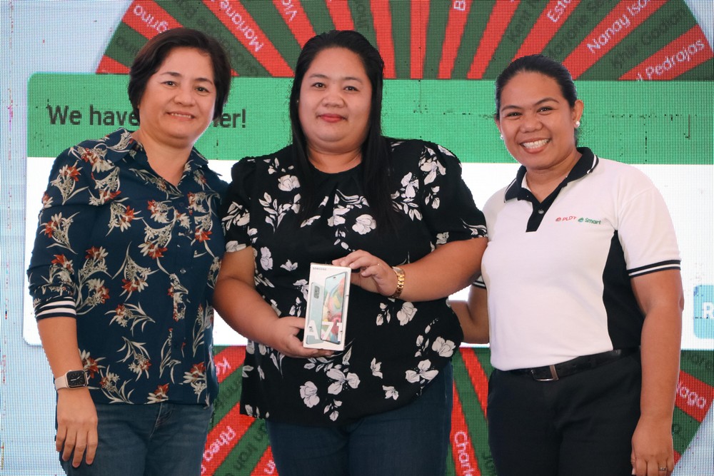 Head of PLDT Enterprise SMBiz Jinky Francisco and Head of Smart Visayas Stakeholder Management Relations Marylou Gocotano pose with one of the winners during the raffle draw. 